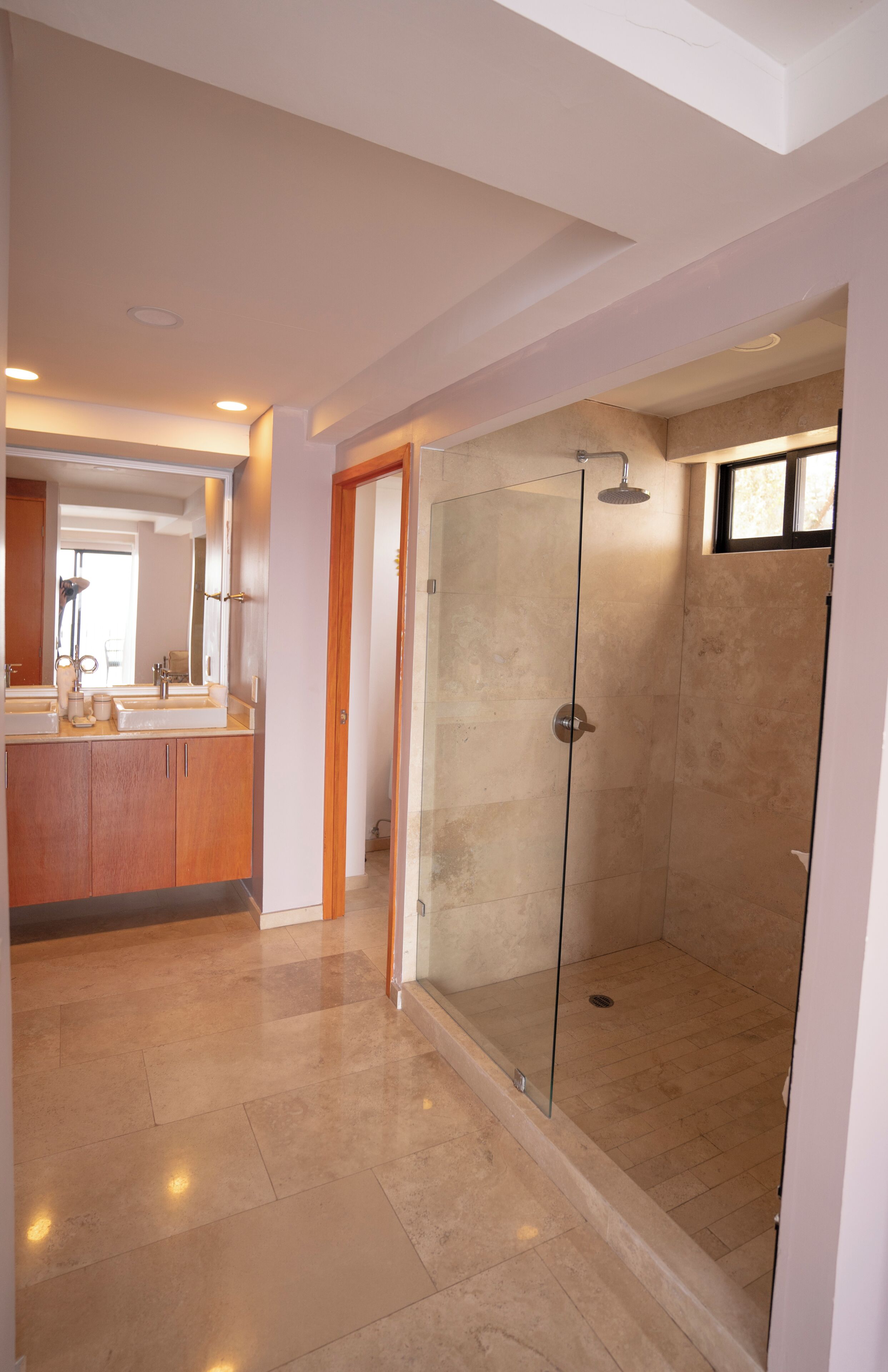 Un baño moderno con ducha de vidrio, tocador con espejo y lavamanos.