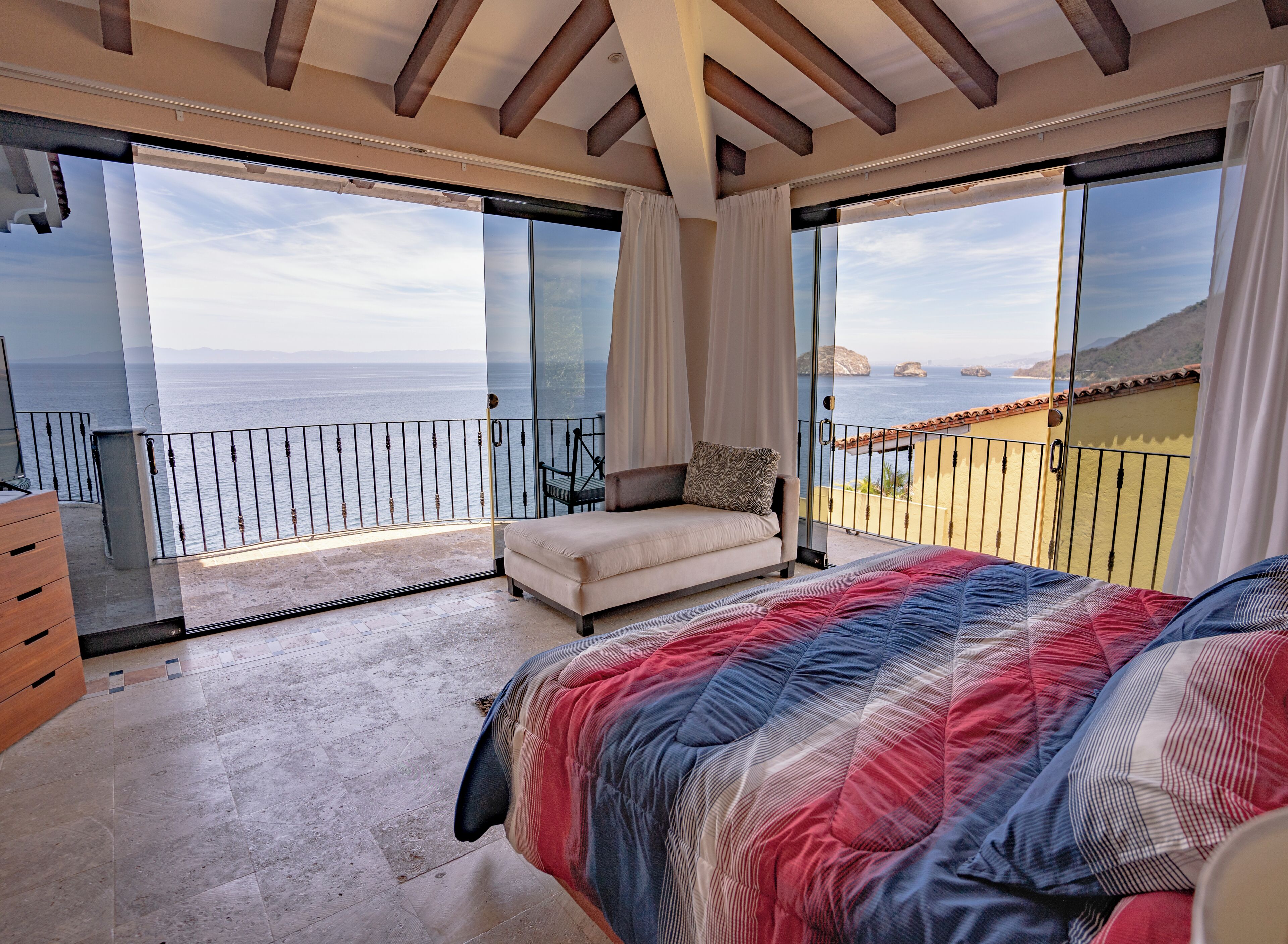 Une chambre avec un grand lit, un canapé et un balcon donnant sur la mer.