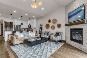 Ein modernes Wohnzimmer mit Sofa, Sesseln, Couchtisch und Kamin.