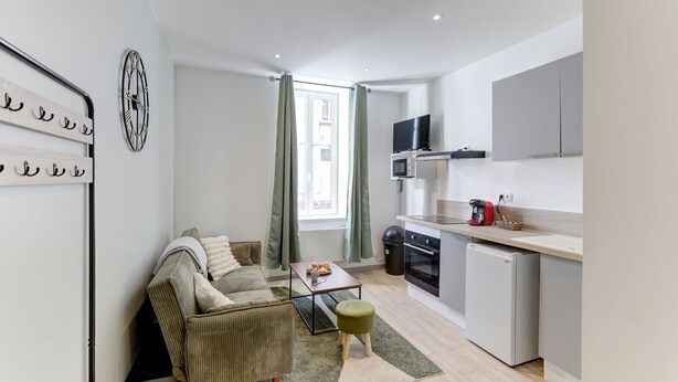 A modern apartment with a living area, kitchenette, and a dining table. - Le Cosy Vert - Proche du Cher (Montlucon)