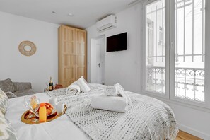 Ein Schlafzimmer mit einem großen Bett, einem Holzschrank, einem Fernseher und einem Balkon mit schmiedeeisernem Geländer.