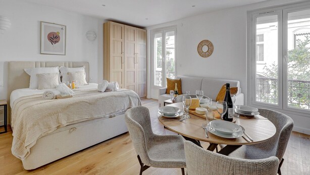 Quarto com cama, mesa de cabeceira e área de refeições com mesa posta para dois.