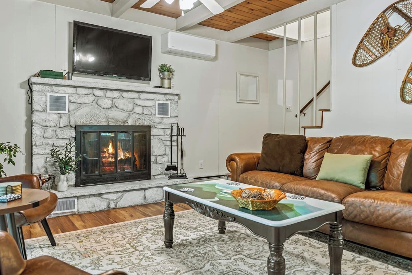 A living room with a stone fireplace, leather sofa, and a billiards table.