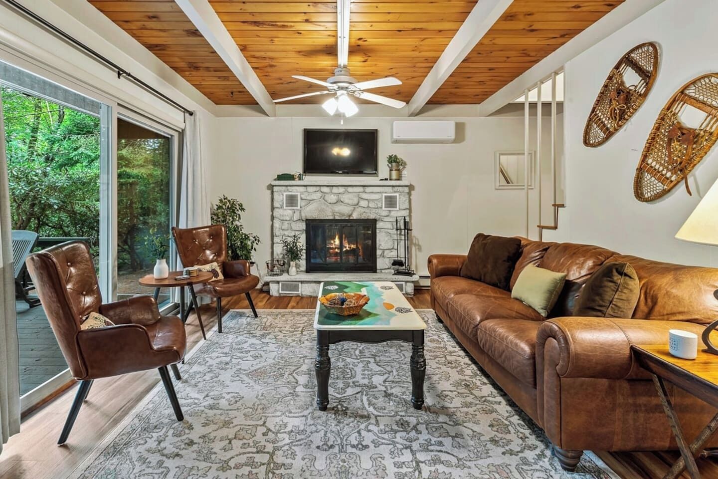 A living room with a fireplace, leather furniture, and a large window.