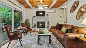 A living room with a fireplace, leather furniture, and a large window.