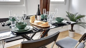 Une table à manger dressée avec de l’assiette verte, des verres et une bouteille de vin Saint-Marguerite.