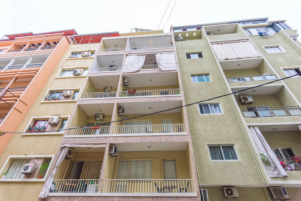 A multi-story residential building with balconies, air conditioning units, and laundry hanging on the exterior.