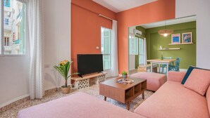 Sala de estar com televisão, sofá e um pequeno espaço de refeições.