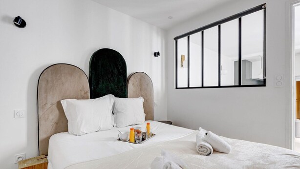 A modern hotel room with a large bed, white bedding, a tray with breakfast items, and a mirror on the wall. - TBS 342 - Superb apartment in the heart of Paris 2 (Paris)
