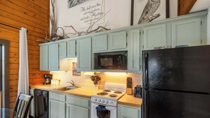 A kitchen with light blue cabinets, a black refrigerator, a stove, and a microwave. - Rustic Shore Cabin Stay for 6 (Branson)