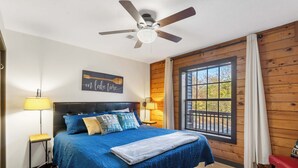 A bedroom with a bed, a ceiling fan, a window with curtains, and a wall-mounted artwork. - Rustic Shore Cabin Stay for 6 (Branson)