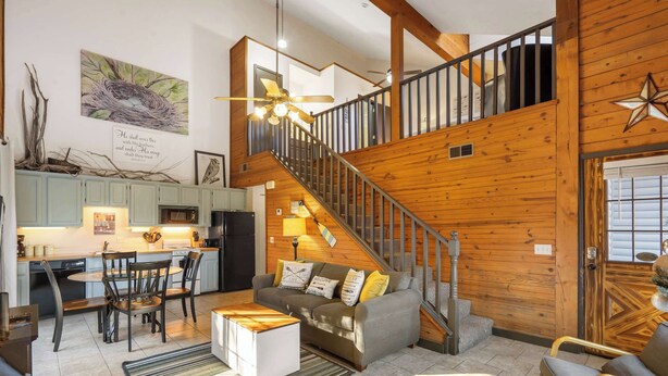 A spacious living area with a staircase, a dining set, and a cozy seating area. - Rustic Shore Cabin Stay for 6 (Branson)
