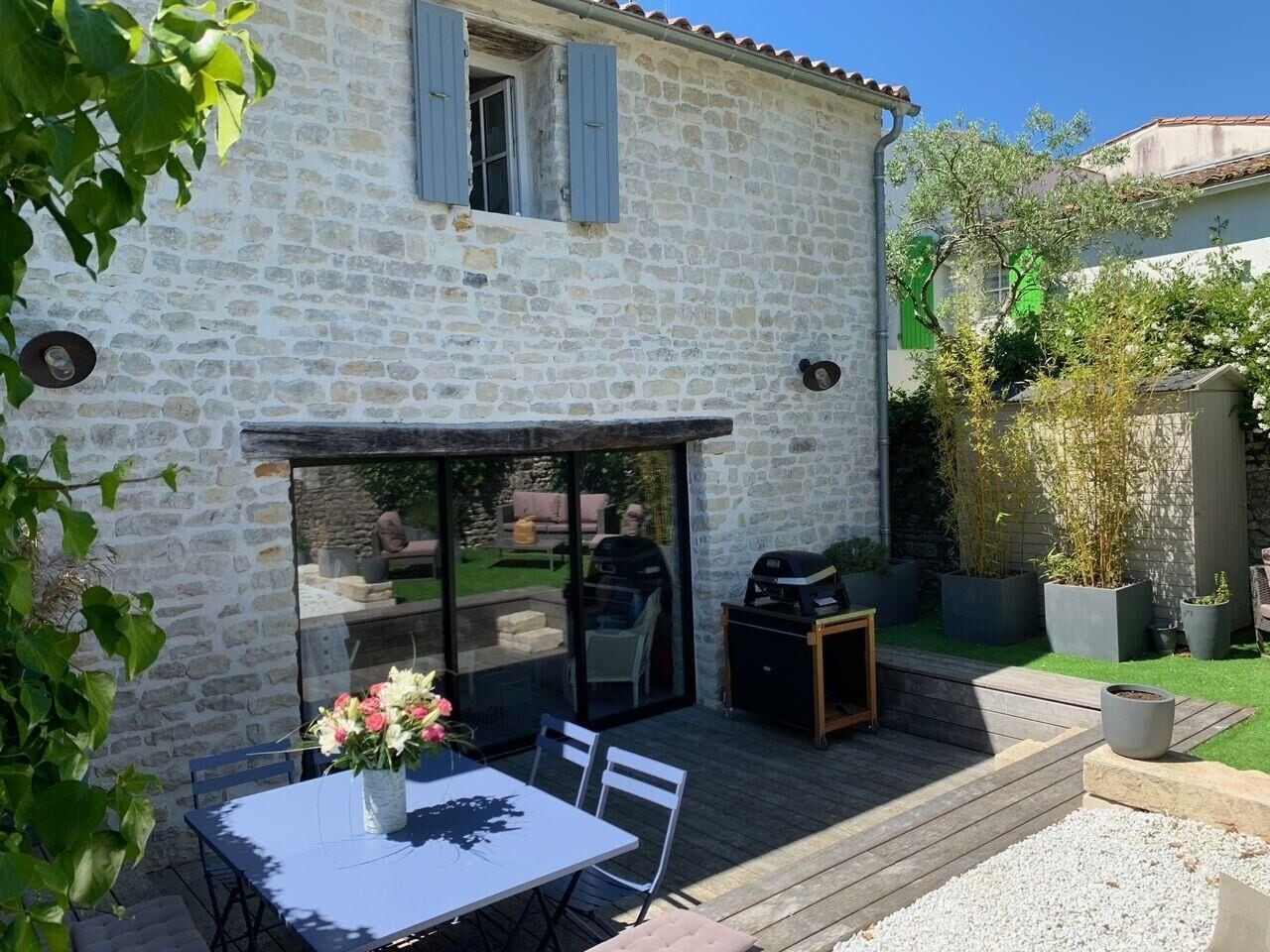 A stone house with a patio area, a table with chairs, and a grill.