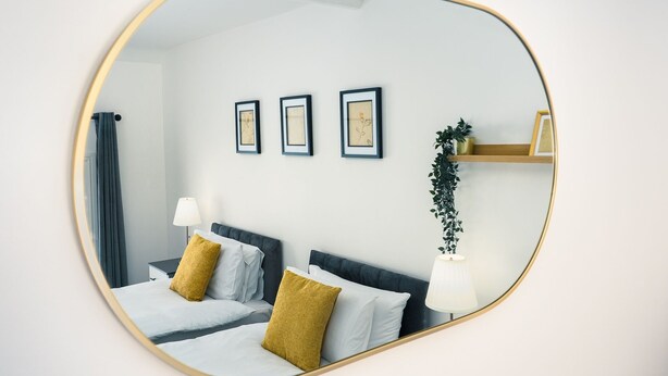 A bedroom with a bed, two bedside tables, a mirror, and three framed pictures on the wall. - Central YeovilStay|Contractors|Free Wi-Fi|Sleeps 8 (Yeovil)