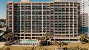 A large hotel with multiple floors, a swimming pool, and a well-maintained lawn. - Cozy studio in charming Myrtle Beach with refreshing oceans view (Myrtle Beach)