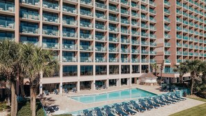 A high-rise hotel with multiple balconies, a swimming pool, and sun loungers. - Cozy studio in charming Myrtle Beach with refreshing oceans view (Myrtle Beach)