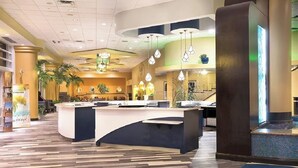 Ein Hotel-Rezeptionsbereich mit einer gebogenen Theke, mehreren Pendelleuchten und einem gefliesten Boden.