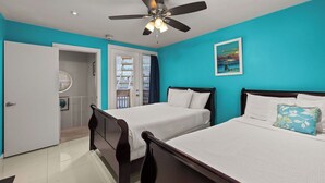Ein Hotelzimmer mit zwei Betten, einem Deckenventilator, einem Bild an der Wand und Blick auf den Außenbalkon.