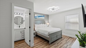A bedroom with a bed, bedside table, lamp, and a large mirror.