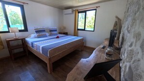 Une chambre à coucher avec un lit en bois, une table de chevet, une lampe, un téléviseur et un mur en pierre.