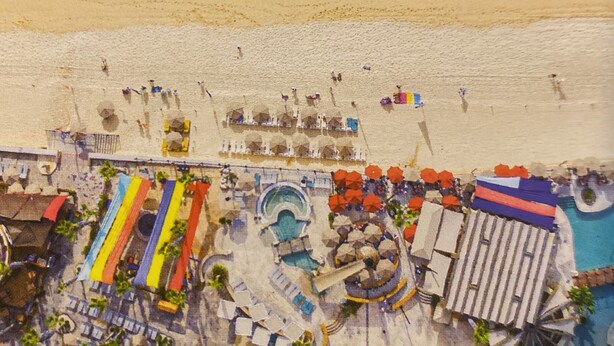 Ein Resort mit Strand, mehreren Schwimmbecken und verschiedenen Sitzbereichen im Freien.