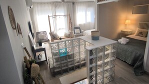 Ein modernes Wohnzimmer mit einer Couch, einem Couchtisch und einem Essbereich mit Tisch und Stühlen. Es gibt einen Deckenventilator und ein Fenster mit Vorhängen.