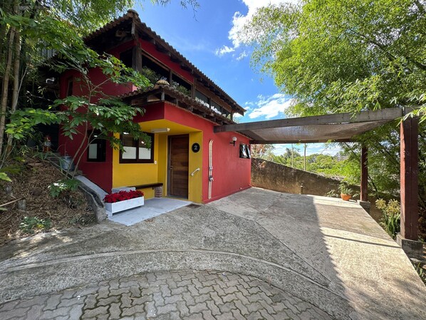 A red and yellow building with a wooden door, a bench, and a ski rack outside.