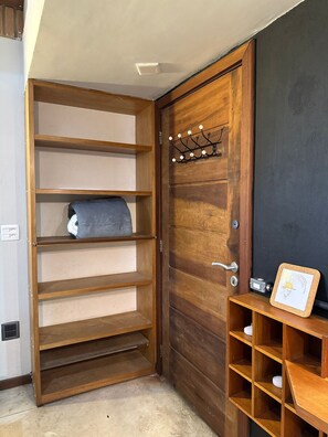 A wooden door with a built-in shelf unit and a small wooden table with a corkboard.