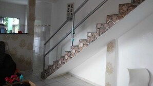 A staircase with stone steps and metal railings, leading to a landing with a white door. - House in Guriri for rent (SAO MATEUS)