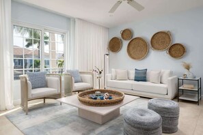 A modern living room with a white sofa, two armchairs, a coffee table, and a large window with curtains. - 2-Min Walk to Grace Bay Beach Condo (Grace Bay)