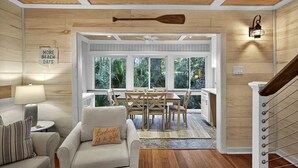 A cozy living room with a wooden ceiling, a dining area with a view of the outdoors, and a staircase with a railing. - Pet Friendly, Tiki Bar, 3 pools, pickleball! (Edisto Island)