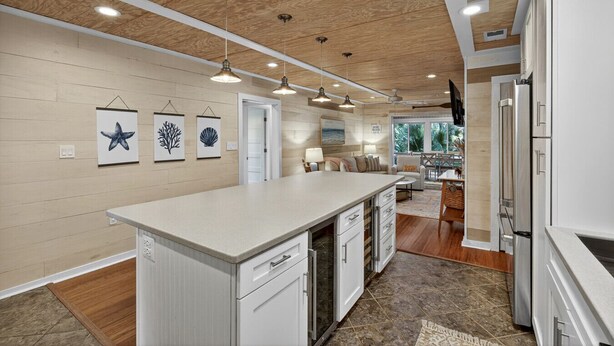 A modern kitchen with a large island, wooden ceiling, and pendant lighting. - Pet Friendly, Tiki Bar, 3 pools, pickleball! (Edisto Island)