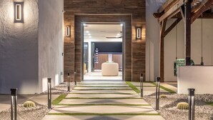 A modern hotel entrance with a concrete pathway, potted cacti, and a wooden ceiling structure. - Modern Arcadia Family Luxury Compound Htd Pool & Spa, Outdoor Kitchen & Fire Pit (Phoenix)