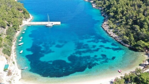 An aerial view of a coastal area with a pier, boats, and a beach. - Apartments Stiniva Hvar (Hvar)