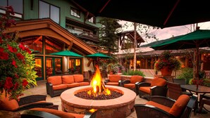 An outdoor seating area with a stone fire pit, wicker furniture, and green umbrellas.