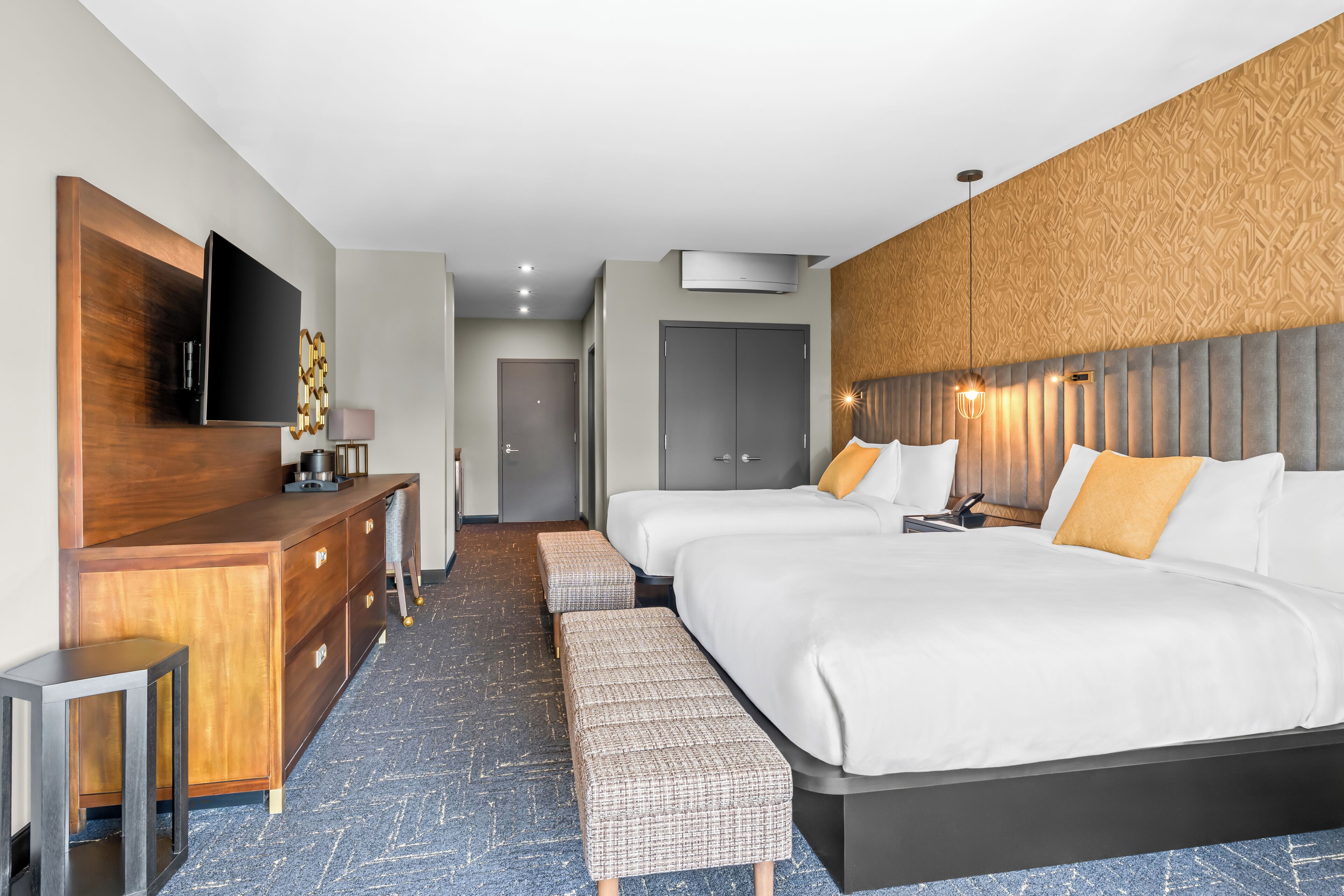 Une chambre d’hôtel avec un grand lit, un bureau doté d’un téléviseur à écran plat, une armoire et un banc.