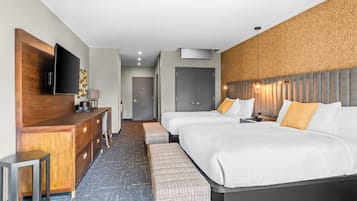 Une chambre d’hôtel avec un grand lit, un bureau doté d’un téléviseur à écran plat, une armoire et un banc.