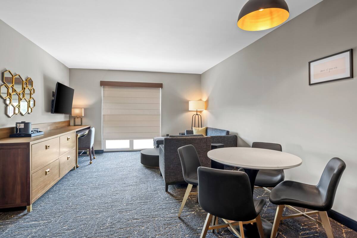 Habitación de hotel con escritorio, silla, sofá y una mesa redonda con sillas.
