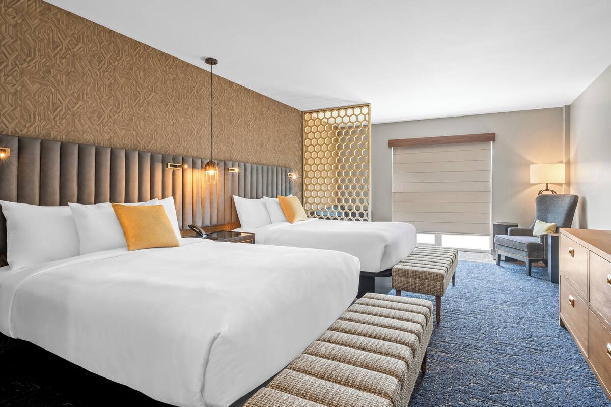 Habitación de hotel con dos camas, una zona de estar y un escritorio.