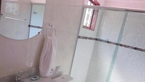 A bathroom with a sink, mirror, and a glass shower enclosure. - Pousada Igarapé (Socorro)