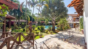 A courtyard with a swimming pool, palm trees, and a stone pathway. - Pousada Igarapé (Socorro)