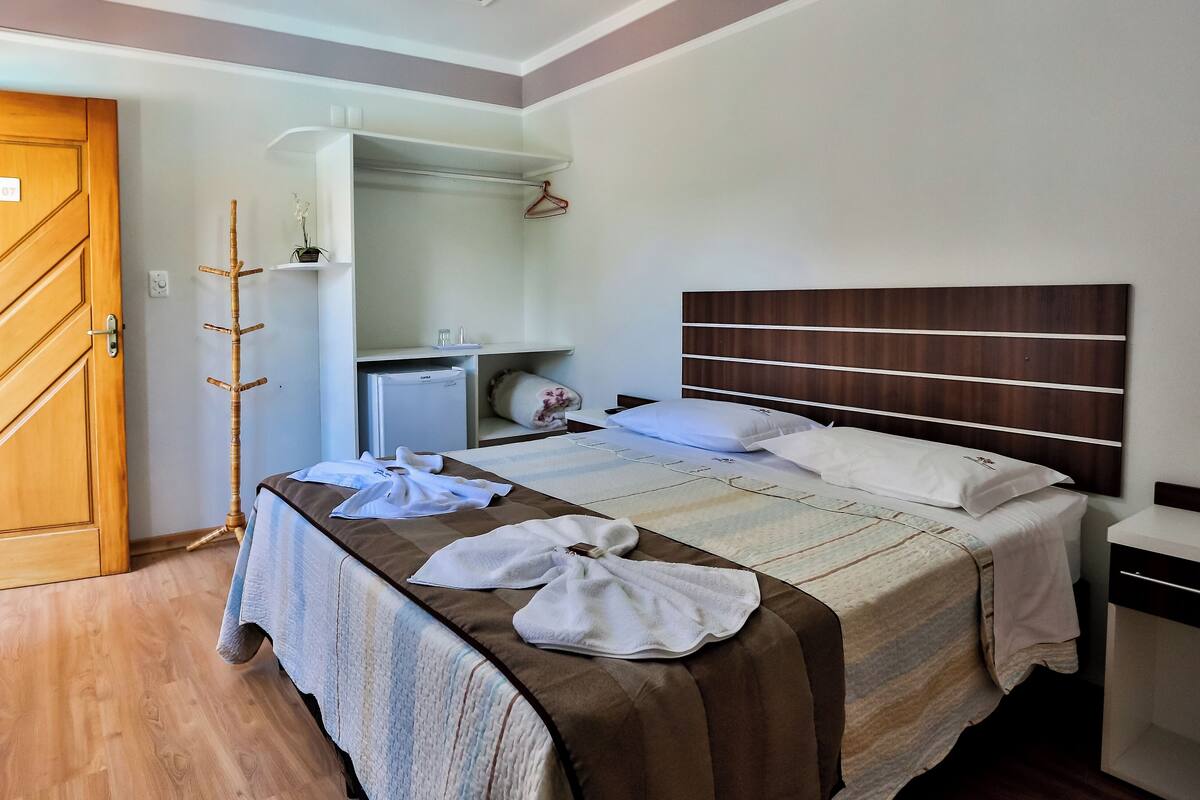 A hotel room with a bed, a wardrobe, a desk, and a mirror.
