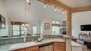 A spacious kitchen with a large island, wooden cabinets, and a built-in dishwasher. There are multiple windows providing natural light and a view of the outdoors. - Premier Keystone 3BR Townhome w/ Resort Access (Keystone)