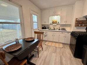 A compact kitchen with white cabinets, a black countertop, and a stove. - The Blue Bungalow 3bed/1bath, centrally located, WiFi, monthly rates available (Ponca City)