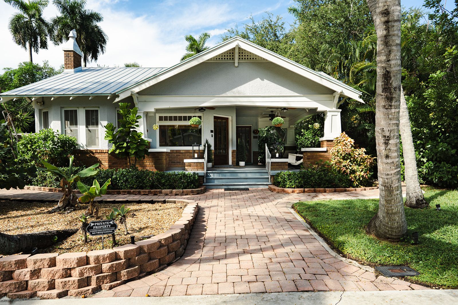 A two-story house with a front porch, a brick driveway, and a well-maintained lawn.