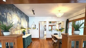 Une cuisine spacieuse avec un plancher en bois, un coin repas avec une table et des chaises, et une vue sur la salle à manger adjacente.
