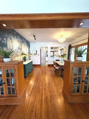 A spacious kitchen with wooden flooring, a dining area with a table and chairs, and a view into the adjacent dining room. - Charming & Comfortable, Historic, only 1/2 mile to vibrant downtown Ft. Myers (Fort Myers)