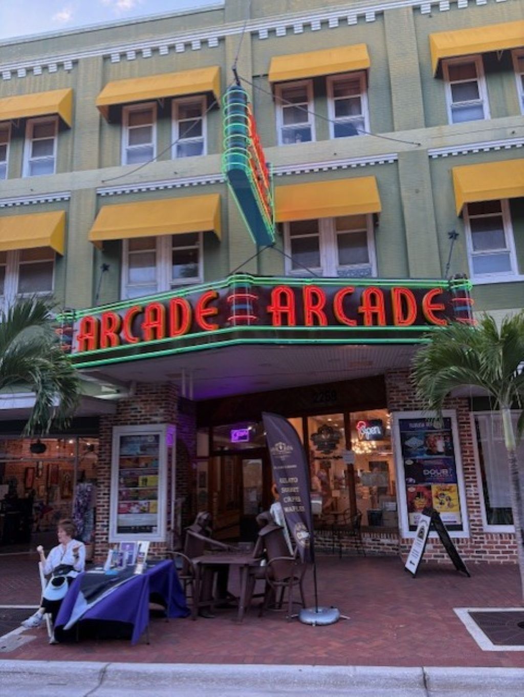 A building with a neon sign reading "Arcade Arcade" and a brick facade.
