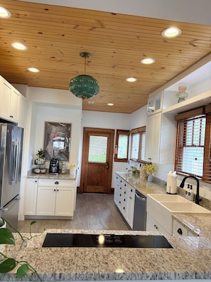 A modern kitchen with wooden ceiling, granite countertops, stainless steel appliances, and a central island with a sink. - Charming & Comfortable, Historic, only 1/2 mile to vibrant downtown Ft. Myers (Fort Myers)
