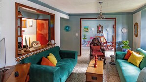 Ein Wohnzimmer mit türkisfarbenen Sofas, einem Holztisch und einem roten Sessel.